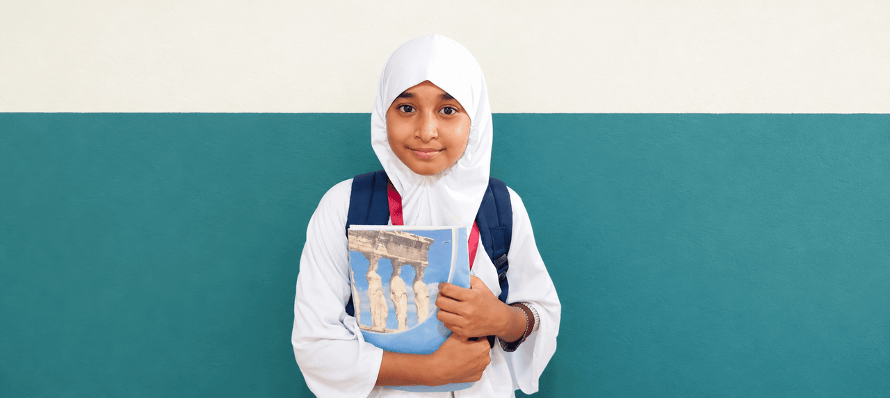 A student of The Progress Academy holding her school book