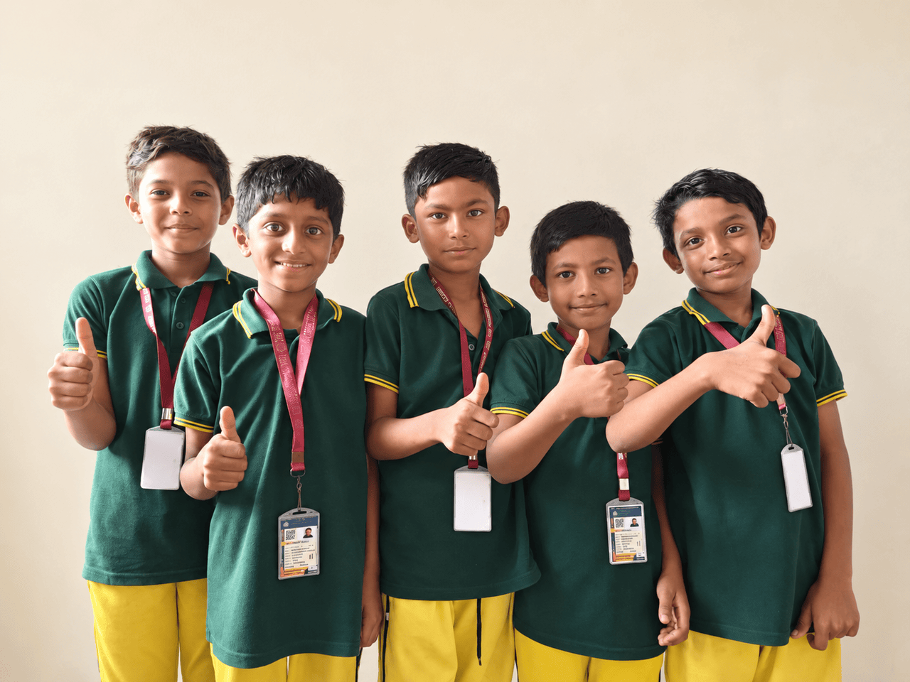 Five students in school uniform smiling and giving a thumbs-up
